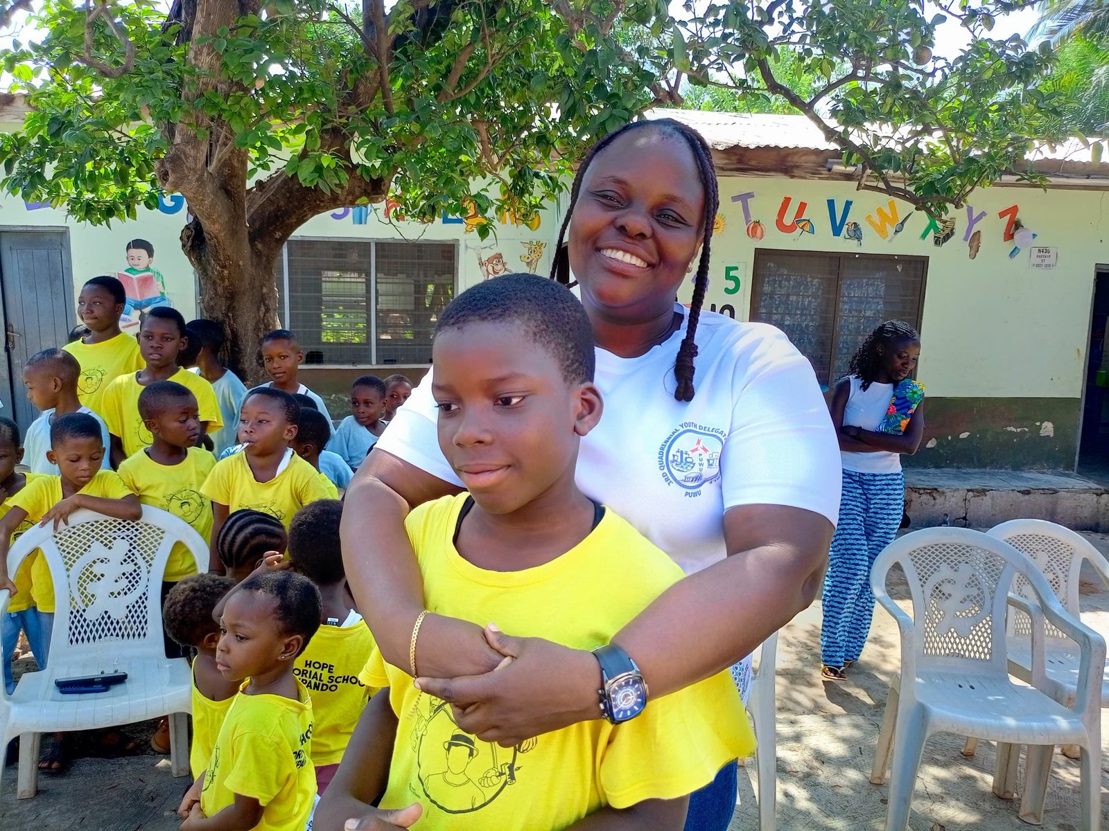 A Ghana program caregiver standing with a child at a school activity