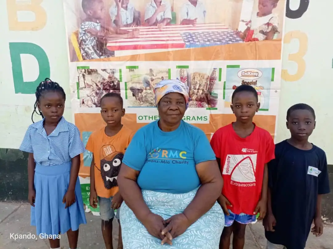 Children standing with a Ryvanz-Mia Charity representative in Ghana